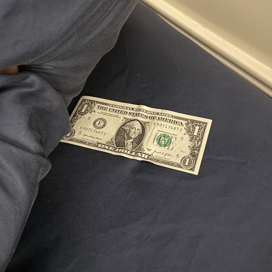A dollar bill tucked under a pillow